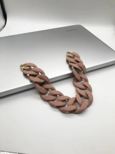 Close-up of matte pink brown acrylic chain strap with gold metal rings on a laptop