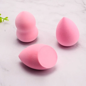 Pink makeup sponge set with teardrop and gourd shapes on white marble surface