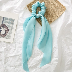 Detailopname van lichtblauwe satijnen scrunchie met lange linten op een esthetische achtergrond
