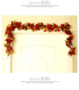Detail of red poinsettia Christmas garland with gold edged leaves on white door frame