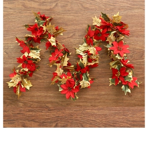Detail of red poinsettia and golden leaves on Christmas vine over dark wood background