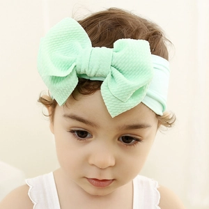 Soft mint green waffle knit baby headband with oversized bow on infant model