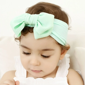Close-up of mint green nylon headband with large textured bow on a baby infant