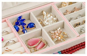 Detail view of pink jewelry box with ring slots and beige velvet interior compartments