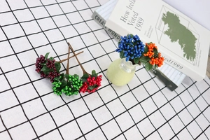 Macro shot of colorful artificial berry stems in purple and blue on checkered cloth