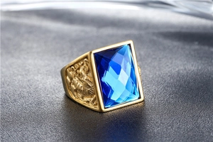 Macro view of men's vintage gold ring with blue gemstone and dragon relief detailing