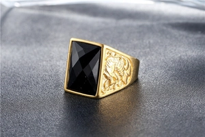 Macro shot of men's vintage gold ring with black gemstone and side totem engraving
