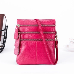 Detail of rose red leather coin purse featuring three gold zippers and pebbled texture
