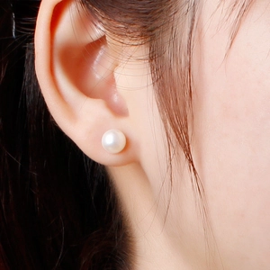 Elegant 925 silver stud earrings with round white pearls on a model's ear