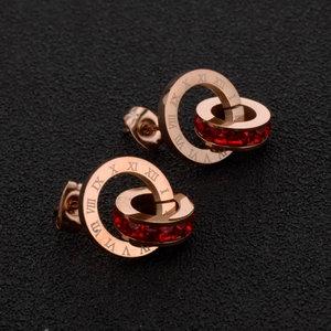 Détail macro de boucles d'oreilles en or rose avec chiffres romains et gemme rouge