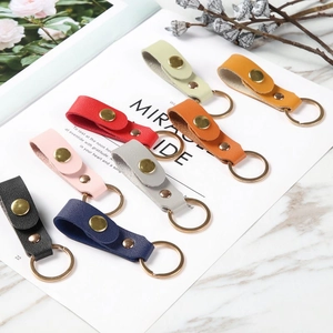 Flat lay of multiple colorful leather keychains on a marble surface with decorative flowers