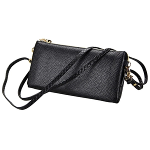 Detail of black lychee grain leather crossbody bag with dual gold zippers and smooth texture