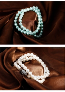 Detailed view of 8mm white and mint green pearl necklaces on elegant brown silk fabric