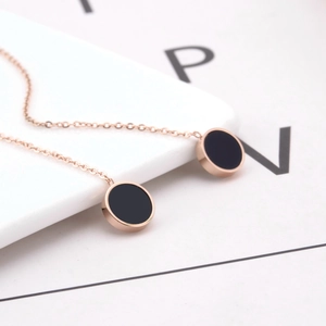 Orecchini pendenti minimalisti in oro rosa con ciondoli neri circolari su basi bianche