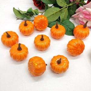 Top view of ten decorative orange mini pumpkins with green leaves on white background