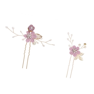 Macro shot of two gold U-shaped bridal hair pins with purple flowers and pearls