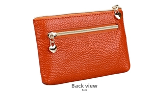 Detail view of orange lychee leather coin purse with heart zipper and back pocket