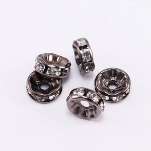 Close-up of five dark grey wheel spacers with clear rhinestones for DIY jewelry beads