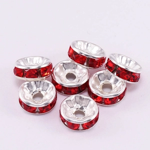 Close-up of silver metal wheel spacers with red rhinestones for DIY jewelry making