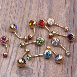 Gold-plated belly button rings with colorful Czech crystals on a wooden background