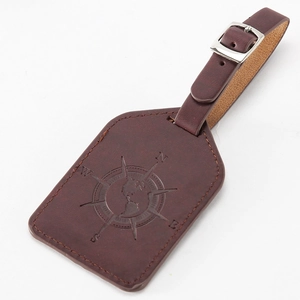 Detailed view of dark brown PU leather luggage tag with embossed compass and world map design