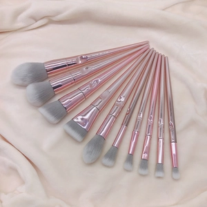 10-piece rose gold makeup brush set with grey bristles arranged on beige blanket