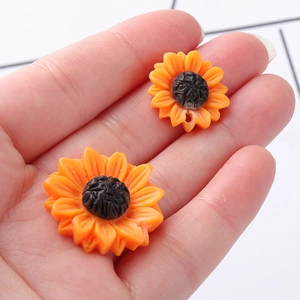Resin daisy sunflower charms for DIY necklaces shown in hand for size scale