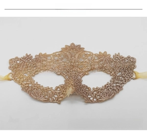 Detailed close-up of intricate gold lace mask with ornate patterns and silk ribbons
