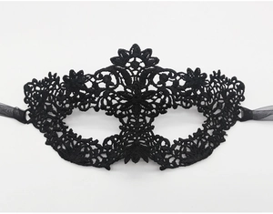 Detail of intricate black lace masquerade mask with ornate floral embroidery and ribbons