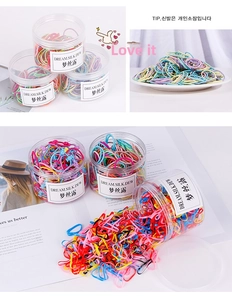 Détail macro d'élastiques à cheveux colorés rangés dans un bocal cylindrique transparent