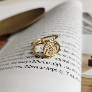 Macro detail of a vintage gold mermaid coin ring placed on an open book page