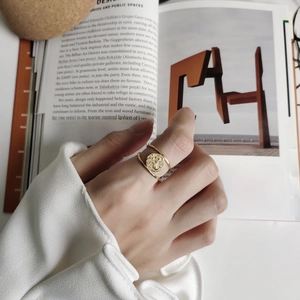 Close-up of golden mermaid coin relief ring on index finger with vintage aesthetic