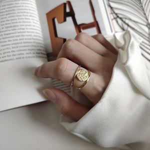 Detail of vintage double-layer gold coin ring with embossed texture on an open book