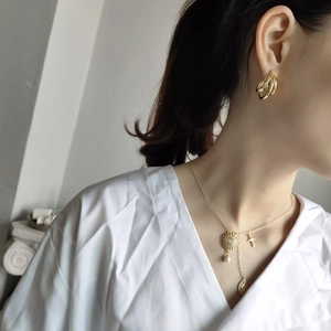 Detailed look at gold triple-hoop earrings and layered necklace with pearl and sun charms