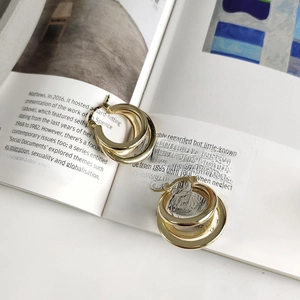 Detail of triple gold-plated hoops earrings on a magazine showcasing chic style
