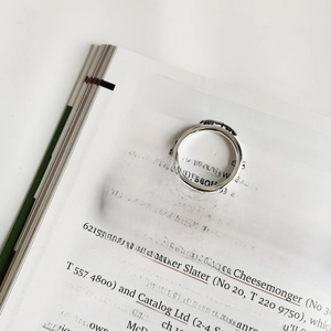 Close-up of dual minimalist S925 sterling silver thin rings on an English magazine