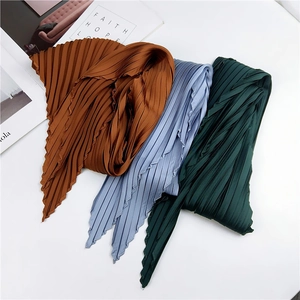Pleated rhomboid silk scarves in caramel, blue, and dark green on a white background