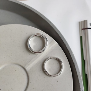 Macro shot of minimalist S925 sterling silver bands on a modern stone base