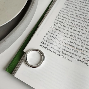 Close-up of two minimalist S925 sterling silver rings on an open magazine page