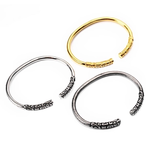 Detailed view of three open bangles in gold, silver, and vintage silver with textured ends