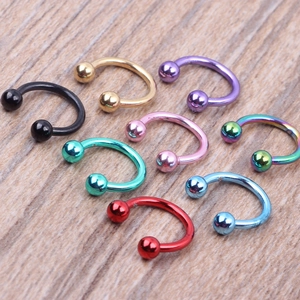 Detailed view of eight colorful horseshoe body piercing rings on a wood surface