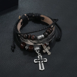 Close-up of multilayer leather bracelet featuring wooden beads and metal cross charms