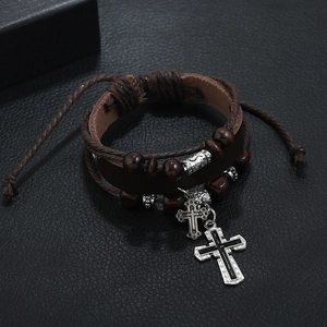 Detailed close-up of multilayer braided leather bracelet with silver cross charms