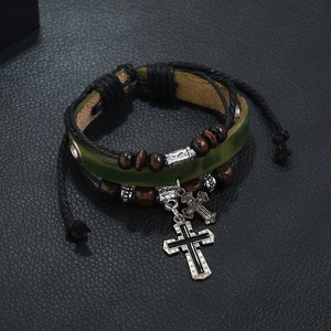 Close-up of green braided leather bracelet with brown wood beads and silver cross pendants