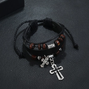Detail of multi-layer braided leather bracelet with wooden beads and silver cross charm