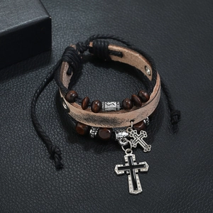 Detail of multi-layer leather bracelet featuring wooden beads and metal cross charms