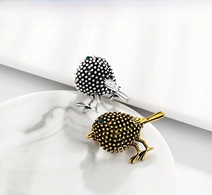 Close-up of vintage bird brooches in gold and silver with green gemstone eyes
