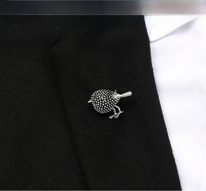 Detail of vintage bird brooch with green gemstone eye on a black suit lapel