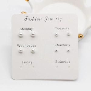 Detailed view of six pairs of graduated pearl stud earrings on a weekly organizer card