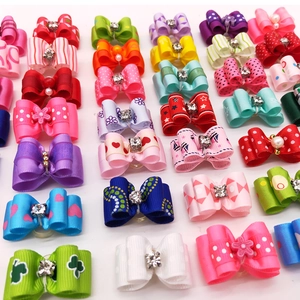 Flat lay of colorful pet bows with rhinestones and varied patterns on white background